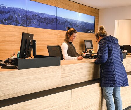 Blick auf zwei Damen bei der Beratung in der Tourist Information in Garmisch-Partenkirchen | © GaPa Tourismus GmbH