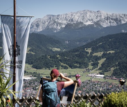 Frau blickt durch ein Fernrohr auf das Wettersteingebirge | © GaPa Tourismus GmbH/ Roadtrip the World