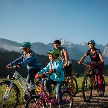 Blick auf eine Familie bei einer Radtour durch Garmisch-Partenkirchen | © Zugspitz Arena Bayern Tirol/ Thomas Marzusch